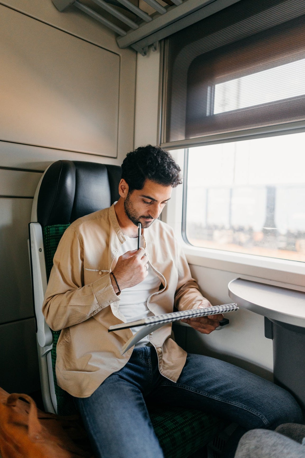 Mann arbeitet konzentriert im Zug mit Notizblock – idealer Moment für Gehörschutz zur besseren Fokussierung unterwegs.